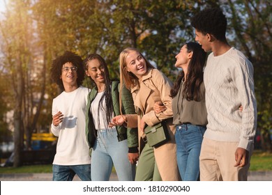 International group of cheerful teenagers laughing while walking by golden park - Powered by Shutterstock