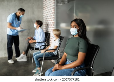 International Group Of Male And Female Patients Waiting For Vaccination Against COVID-19, Having Conversation With Male Doctor African American Woman In Face Mask Sitting At Hospital Hall