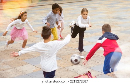 International Group Of Sports Tweenagers Having Fun Together Outdoors, Playing Football In School Yard After Lessons On Autumn Day.