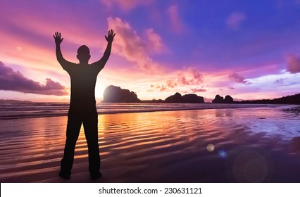 International human rights day concept: Silhouette fulfillment man raising hands for seeking God against ocean sunset background. Pak Meng Beach, Trang Thailand, Asia