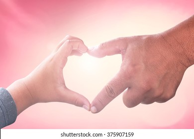 International Human Rights Day Concept: Father And Child Hands In Shape Of Heart On Beautiful Red Sunset Background