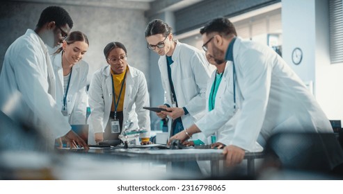 International Manufacturing Project Managers Discussing Data Gathered in Product Analysis Using Laptop and Tablet Computers. Group of Young Professional Specialists Brainstorming, Solving Problems - Powered by Shutterstock