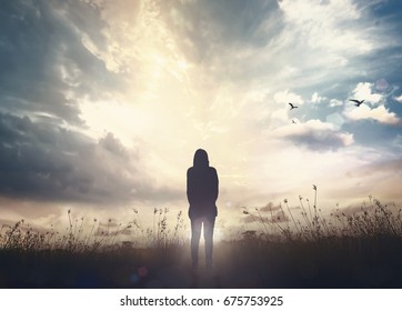 International migrants day concept: Alone victim woman standing on black autumn sunset background
