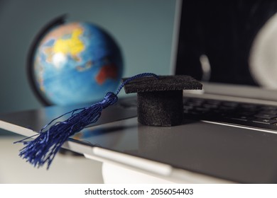 International online education concept. Graduation hat and globe on laptop