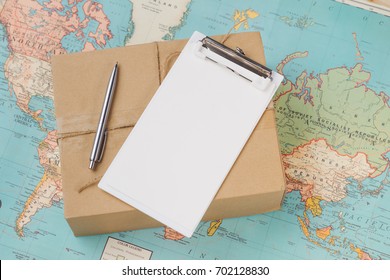 International Shipping. Cardboard Box On The Geographical Map Background