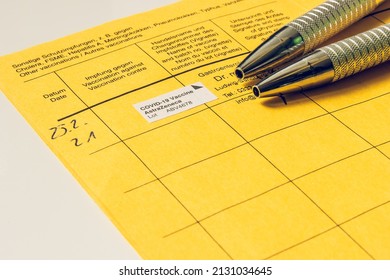 International Vaccination Certificate From The World Health Organization. Open Vaccination Book With Two Metallic Ballpoint Pens. Manufacturer, Vaccine And Batch Number