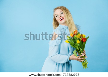 International women day, eight march. Beautiful portrait of pretty woman blonde hair with red yellow tulips, fashion make up, elegant dress. Mother day. On blue