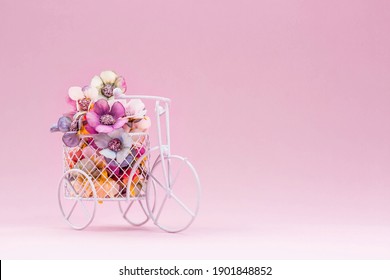International Women's Day. Banner, flyer, postcard small bicycle with a bouquet of flowers. Flowers and a vintage bicycle on a pink background. Flower delivery. Online order from a flower shop.