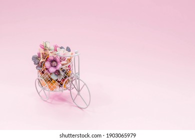 International Women's Day. Banner, flyer, postcard small bicycle with a bouquet of flowers. Flowers and a vintage bicycle on a pink background. Flower delivery. Online order from a flower shop.