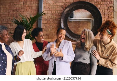 International Women's Day portrait of cheerful multiethnic mixed age range businesswomen celebrating