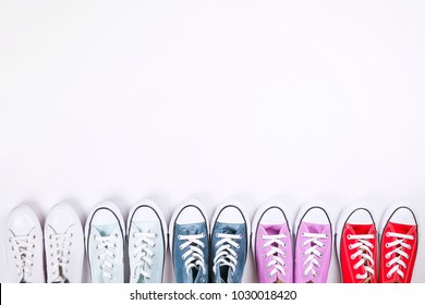 International Womens Day Sale Clearance. Variety Row Of Different Colorful Casual Shoes On White Background. Spring-summer Collection. White, Blue, Purple, Red Low Top Sneakers. Copy Space, Top View.