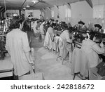 Interned Japanese American, Sumiko Shigematsu, standing at left, supervises fellow internees working at sewing machines at Manzanar Relocation Center, California. 1943 photograph by Ansel Adams.
