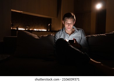 Internet addiction. Online shopping at night. Young Caucasian male at home with cell phone. Guy 30s virtual chat user. messenger in the smartphone. Gadgets in a person's life.
