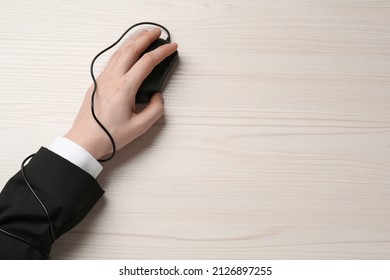 Internet addiction. Top view of man using computer mouse at wooden table, hand tied to device with cable