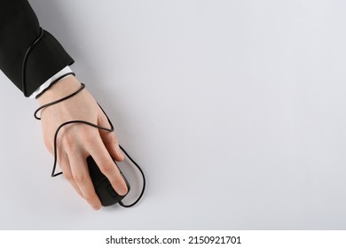 Internet addiction. Top view of man using computer mouse on white background, hand tied with cable