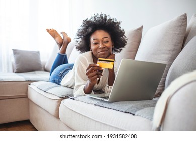 Internet Banking, Online Shopping And Technology Concept -Happy Smiling African American Woman Sitting On Sofa With Tablet Pc Computer And Credit Card At Home