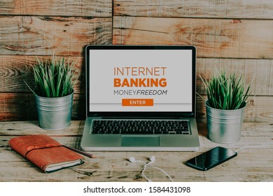 Internet banking website in a laptop computer screen, on a wooden office desk.
