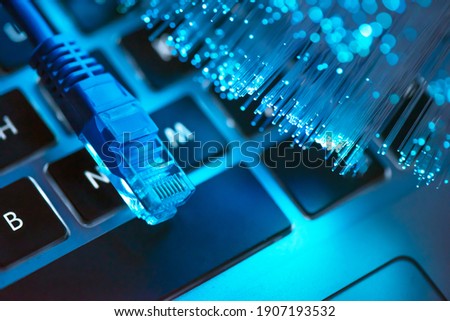 Internet cable, RJ-45 plug on laptop keyboard. High speed fiber optic internet concept