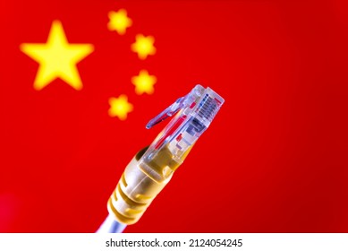 Internet in China concept. Ethernet cable connector and blurred Chinese flag on the background. Selective focus.