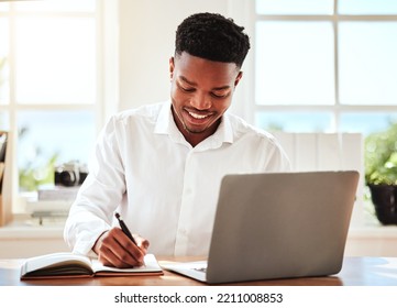 Internet, Laptop And Black Man Writing In Notebook, Happy Freelance Worker. African Businessman With Smile Doing Online Research, Taking Notes For Startup Idea Or Project At Desk And In Modern Office