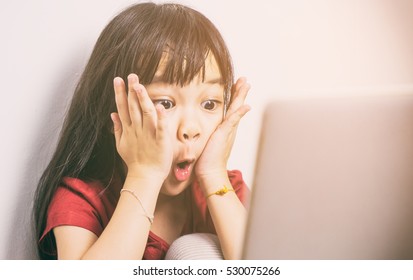 Internet And Online Social Media Safety Concept. Little Asian Girl Is Shock With What She See On The Internet. Parent Should Be More Careful On How Kid Using The Online Computers.