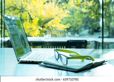Internet Project Work on Laptop Computer bleiben auf schwarzem Holztisch in offenen Raum gemütliche Büro oder Home mit sonnigen Garten außerhalb Fenster