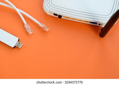 Internet router, portable USB wi-fi adapter and internet cable plugs lie on a bright orange background. Items required for internet connection