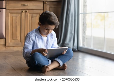 Internet Safety. Little School Age Boy Sit By Window On Floor With Heating Engaged In Chatting Blogging On Digital Touchpad Pc Playing Mobile Videogame. Tween Kid Browsing Web On Electronic Pad Gadget