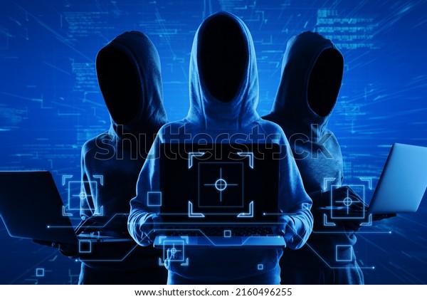 Internet security and personal data theft concept\
with blue shadows faceless hackers in hoody using laptop and\
abstract virtual technological\
symbols