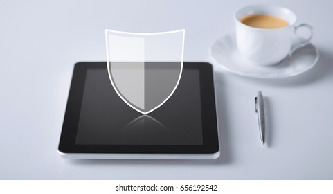 internet security, technology and cyber protection concept - virtual antivirus program shield icon over tablet pc computer with cup of coffee and pen