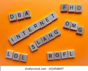 Internet slang, acronyms ROFL, (Rolling on floor laughing) LOL (Lots of Laughs), OMG, FHO and DBA in wooden alphabet letters on a bright orange background.