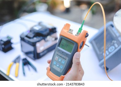 Internet technicians are measuring light signals using power meter tools to measure light intensity with accuracy and precision. - Shutterstock ID 2143783843
