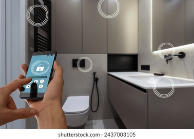 Internet of things. Focus on modern smartphone with blank mockup screen for smart home control system interface in young female customer user hand. Blurred living room interior on background. Close up