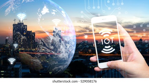 Internet of things , iot , smart home , smart city and network connect concept. Human hand holding white phone and iot icon with city sunset view and earth furnished by NASA. background and wifi icons - Shutterstock ID 529058176