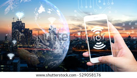 Internet of things , iot , smart home , smart city and network connect concept. Human hand holding white phone and iot icon with city sunset view and earth furnished by NASA. background and wifi icons