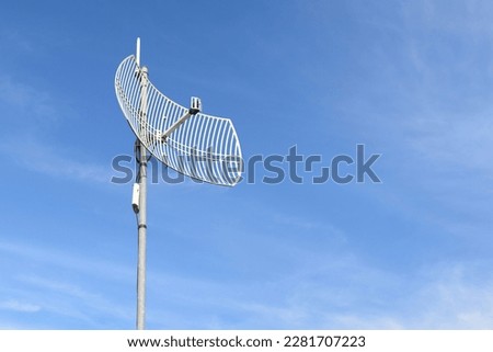 Internet wireless wifi receiver and repeater installed on metal pole on the roof of the building to service internet to users in local village, soft and selective focus.