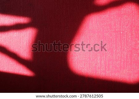The interplay of light and shadow on a bright red textured surface.