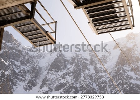 An interpretation panel stands below bright alpine peaks and snowfields near the Aiguille du Midi viewpoint.