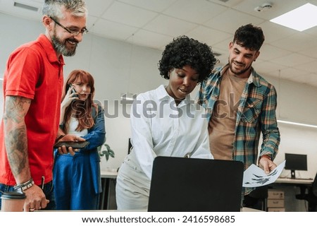 An interracial businesswoman is typing on a laptop and working on a project while her coworkers are helping her with data entry. A team is collaborating on a market research at company. Copy space.