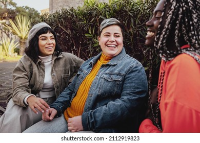 Interracial cheerful group of happy girls having fun talking together in the park talking and having fun sitting on a bench in the park