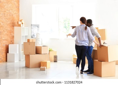 Interracial couple with boxes indoors. Moving into new house - Shutterstock ID 1131827024