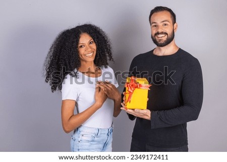 Interracial couple, Caucasian man and black woman, Brazilian. boyfriend gifting his girlfriend.