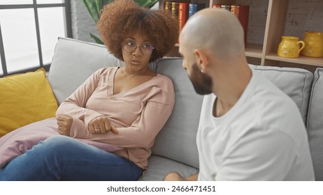 Interracial couple converses seriously in a cozy, modern living room, reflecting relationship dynamics. - Powered by Shutterstock