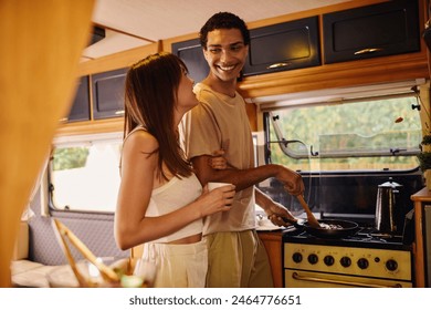 An interracial couple cooking together inside a camper van on a romantic getaway, surrounded by cozy vibes. - Powered by Shutterstock