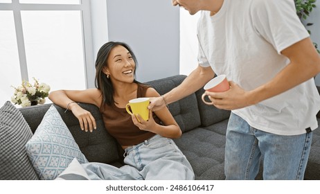 An interracial couple enjoys coffee together in a cozy, modern living room, displaying love and family unity. - Powered by Shutterstock