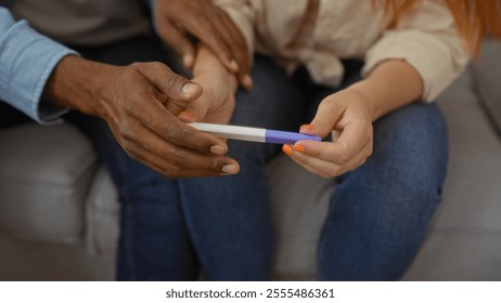 Interracial couple holding pregnancy test in cozy living room, suggesting excitement and bonding in their home. - Powered by Shutterstock