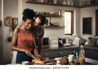 Interracial couple, kiss and cooking in kitchen for morning breakfast, love or caring relationship at home. Man kissing woman while making food, romantic meal or cutting ingredients on table in house - Powered by Shutterstock