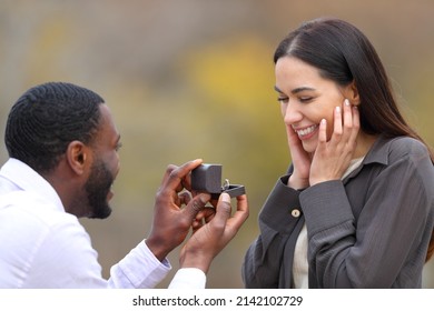 Interracial Couple Proposing Marriage Standing In A Park