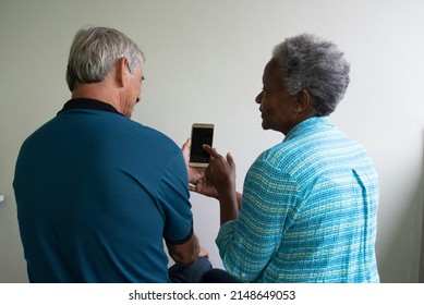 interracial couple of retirees looking at cellphone.