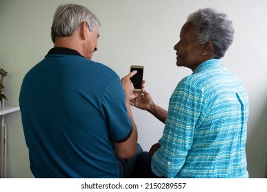 interracial couple of retirees looking at cellphone.